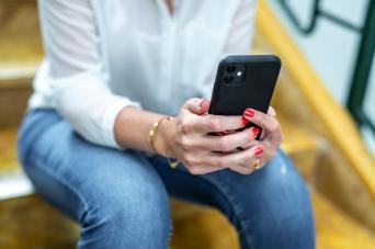 © Landratsamt Zollernalbkreis Frau sitzt auf einer Steintreppe mit einem Handy in der Hand