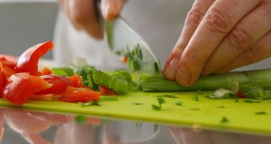 Schneidebrett mit Paprika und Lauch der geschnitten wird