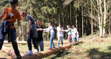 Kinder, die über einen Baumstamm balancieren