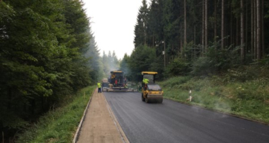 frisch geteerte Straße zwischen Tannenbäumen